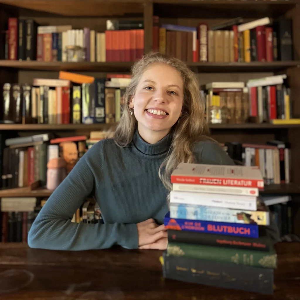 Portrait von Feli mit einem Stapel Bücher