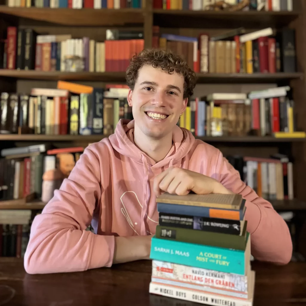 Portrait von Mathi mit einem Stapel Bücher